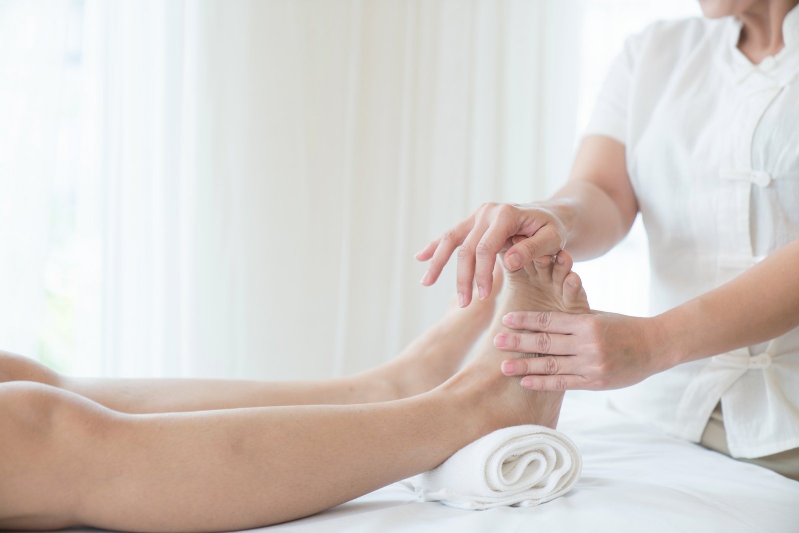 Woman having a pedicure treatment at a spa or beauty salon with the pedicurist massaging the soles of her feet with a pumice stone to cleanse dead skin and stimulate the tissue Workplace massage Foot massage