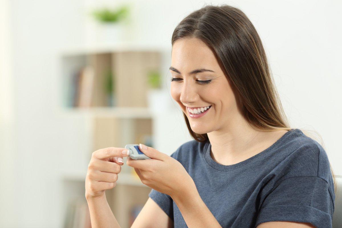 Happy diabetic girl checking blood sugar level employee health screening
