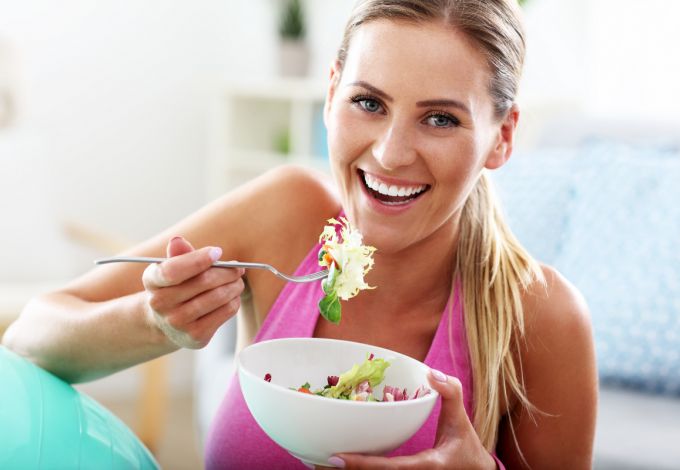 Fit woman eating healthy salad after workout nutrition for wellbeing